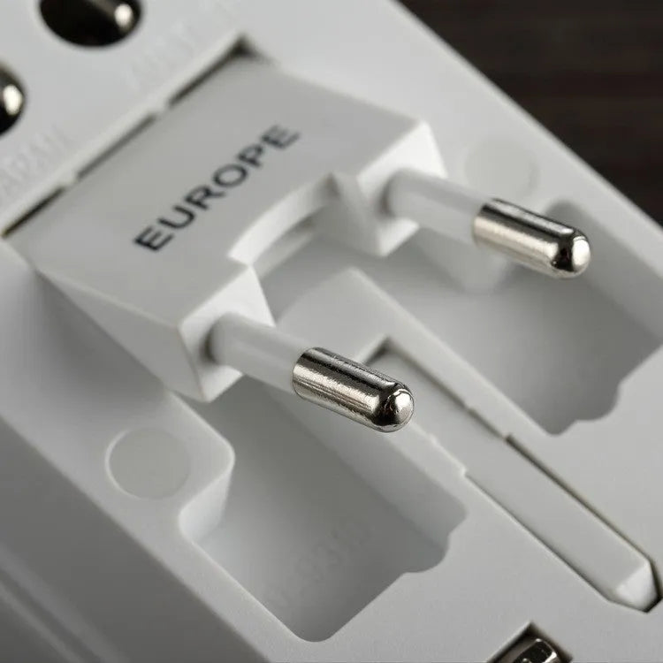 White universal travel plug adapter with dual USB ports and interchangeable UK EU US AU plugs on a plain background