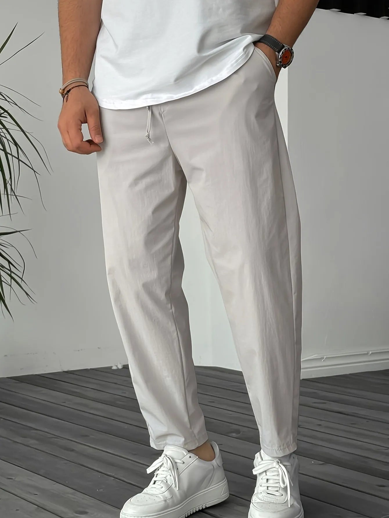 Man wearing khaki straight-leg drawstring trousers with a tonal ribbon pocket detail.