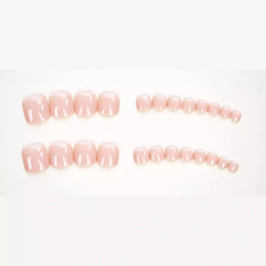 Finished plastic toe nail stickers in J-52 skin colour with glue tube on white background.
