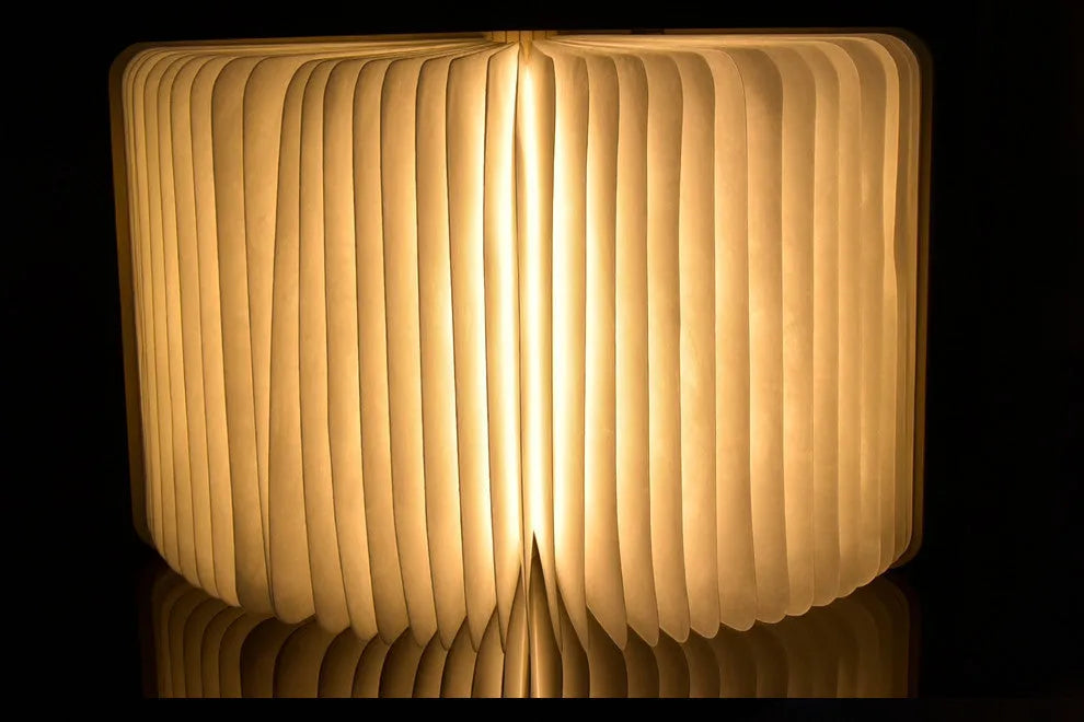 Walnut cover LED book light open at an angle showing white light pages on a surface
