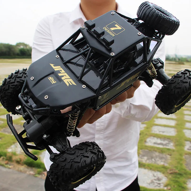 Black and silver remote control off-road car on rough terrain showing four-wheel drive and climbing capability.