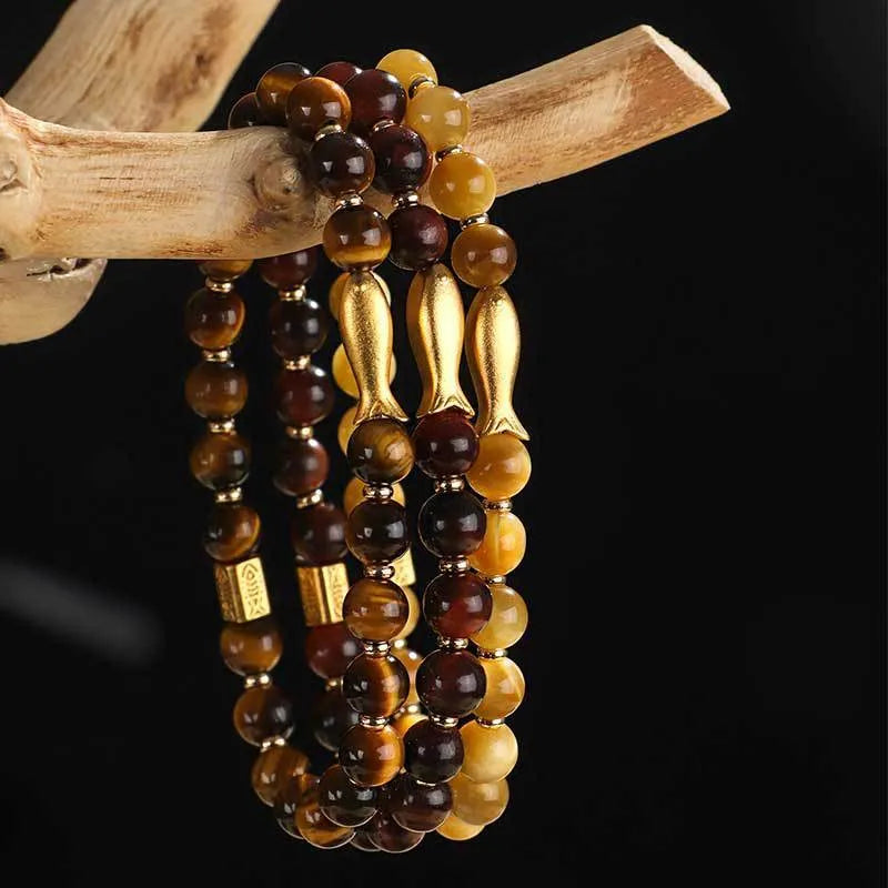 Close-up of a women's bracelet with small fish-shaped Tiger Eye stone beads in yellow, red, or gold colours.
