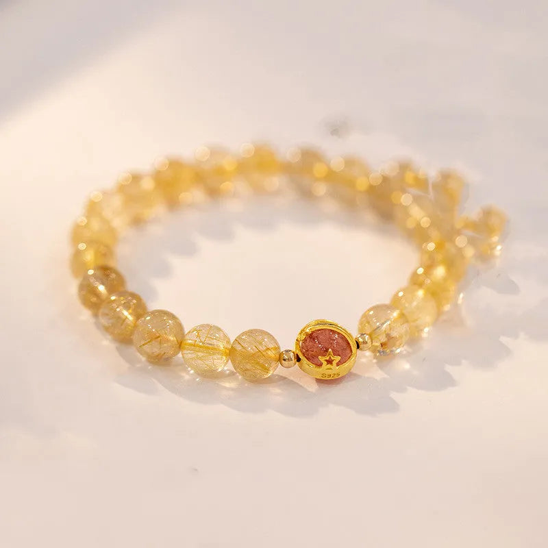 Citrine and gold rutilated quartz bracelet with diamond-cut beads in 6mm or 8mm size on a wrist.