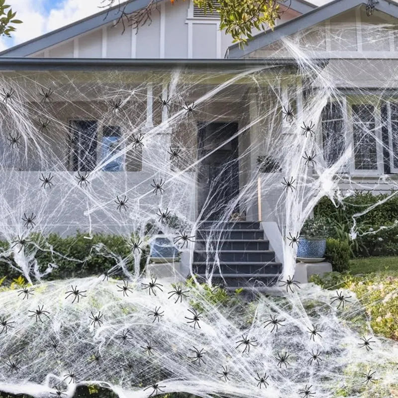 White cotton Halloween spider web decoration draped with plastic spiders for haunted house party decor.