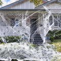 White cotton Halloween spider web decoration draped with plastic spiders for haunted house party decor.