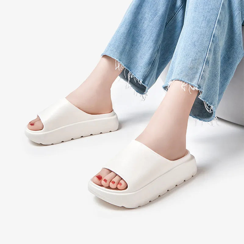 Women's beige fish mouth style EVA slippers with a thick sole, shown on a sandy beach background.