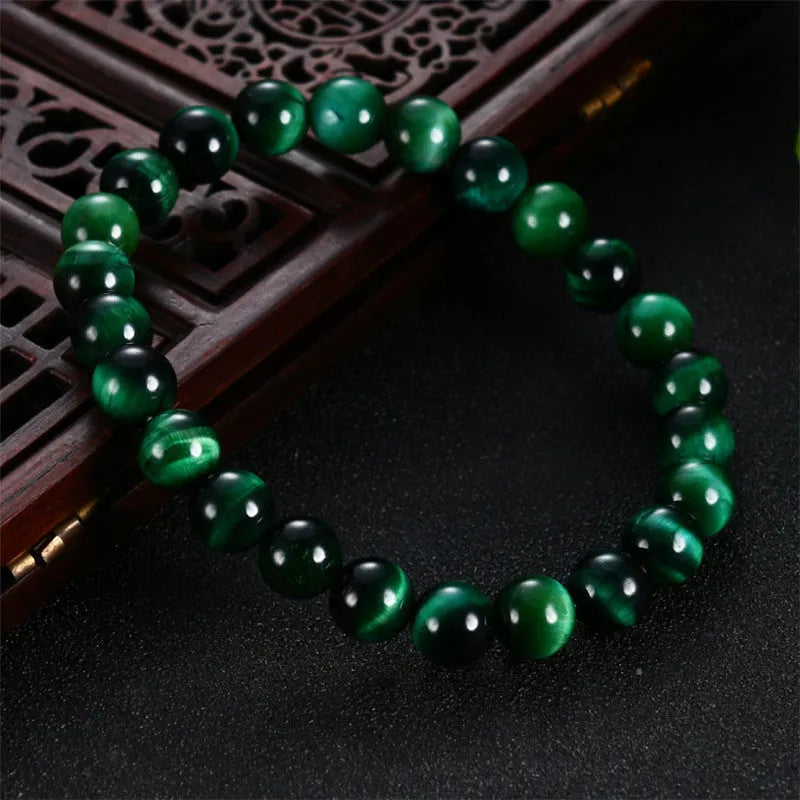 Green tiger eye stone bracelet with geometric shaped beads on a white background.