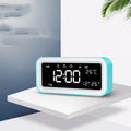 Blue rectangular LED alarm clock with digital display on a table.
