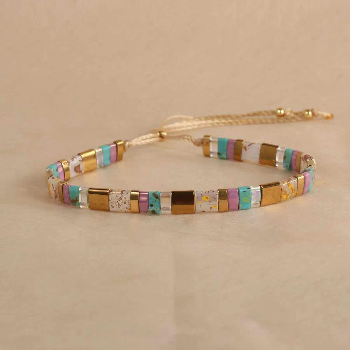 Geometric round glass bead bracelet in five colour options on a wrist.