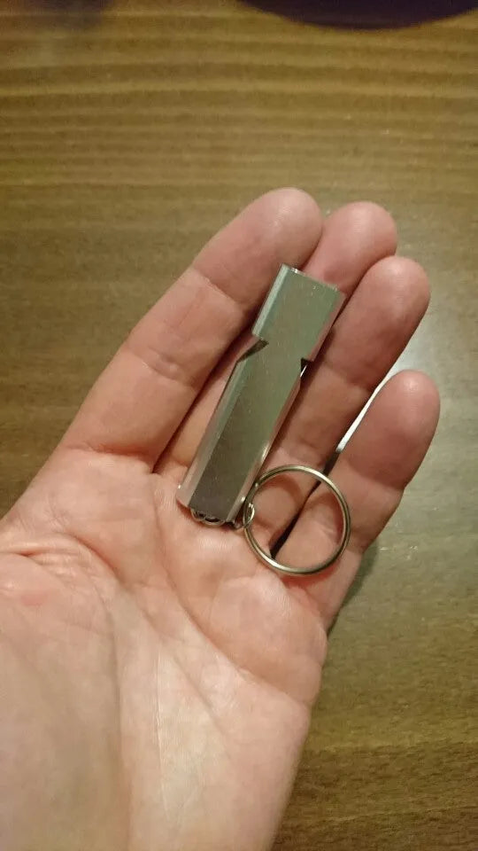 Silver and gold coloured aluminium alloy double-hole outdoor survival whistle with keychain.