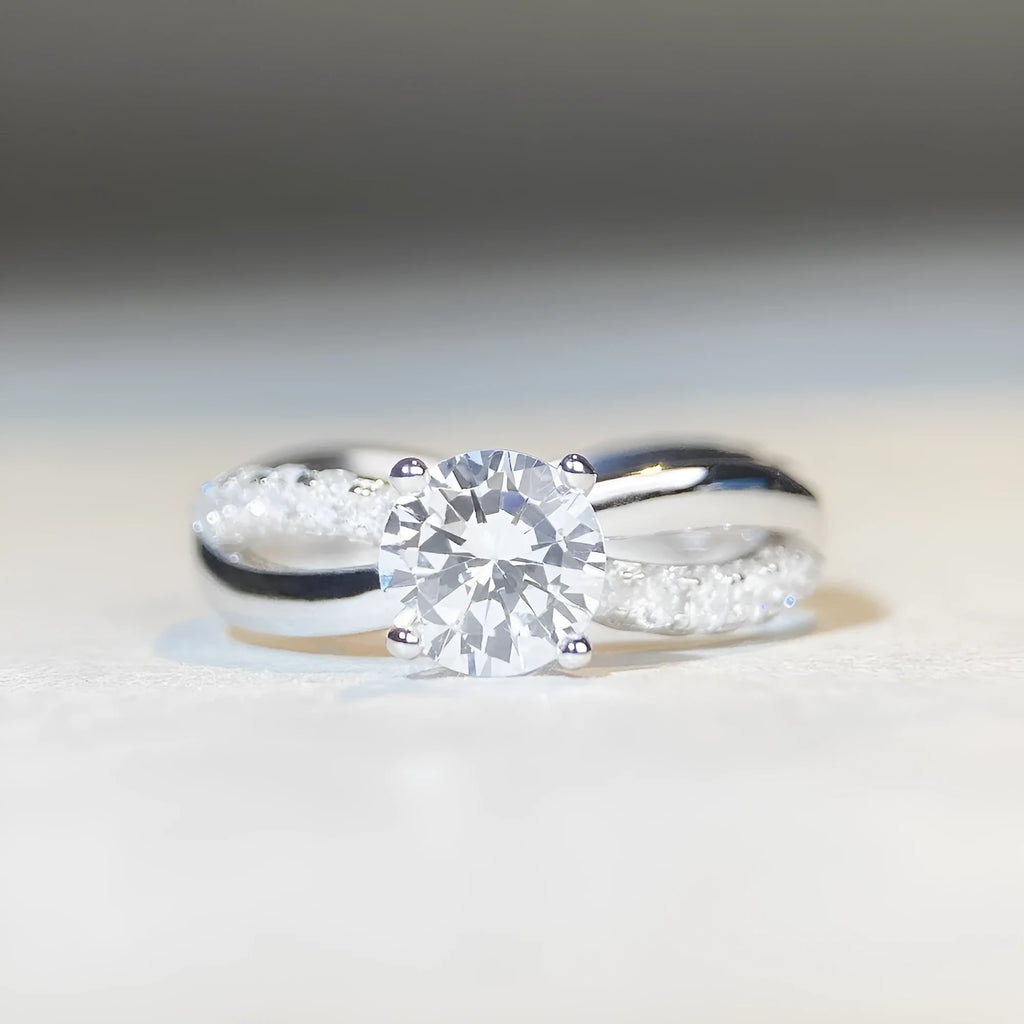Geometric silver ring with a 1 karat moissanite stone in a four-claw setting and twisted arm band.