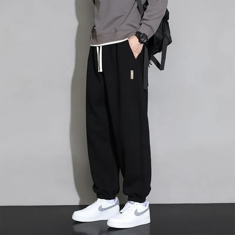 Men's loose grey cotton polyester sports trousers with elastic drawstring waist, laid flat.