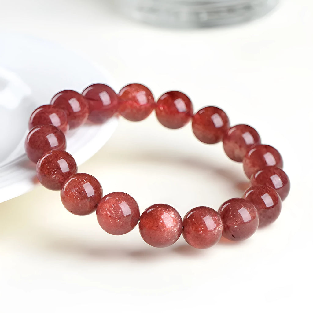 A stretch bracelet with round, pink strawberry quartz beads on an elasticated cord, shown in different size options.
