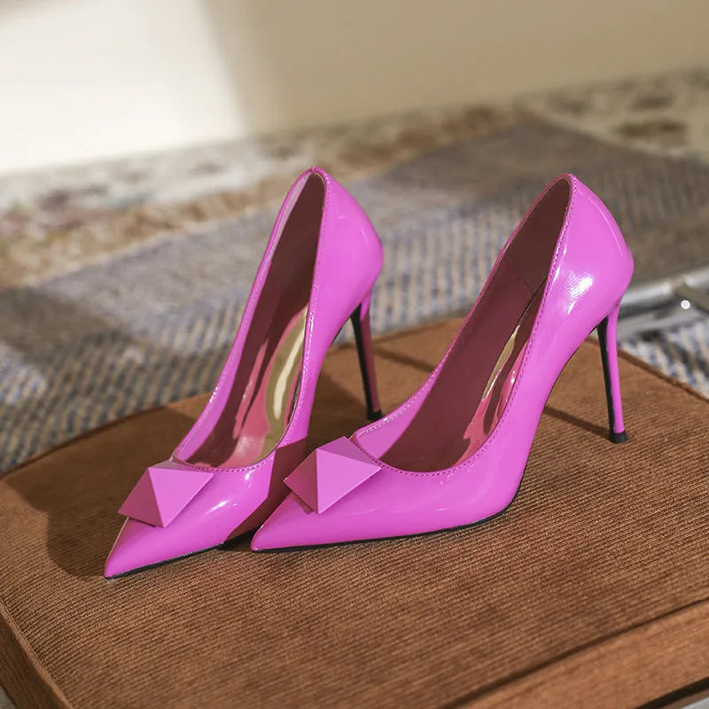 Women's pink patent leather pointed toe stiletto high heels with a buckle.