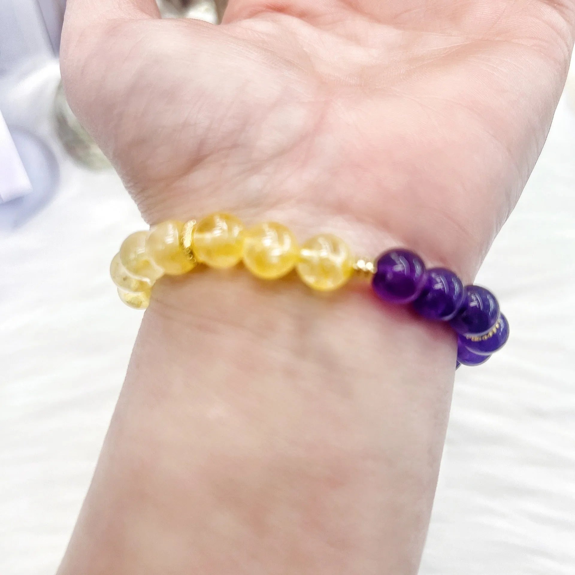 Handmade women's bracelet with yellow and purple amethyst crystals on wrist