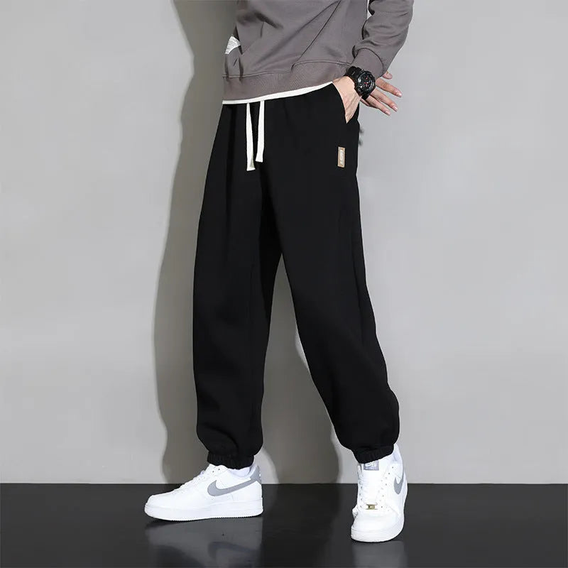 Men's loose grey cotton polyester sports trousers with elastic drawstring waist, laid flat.