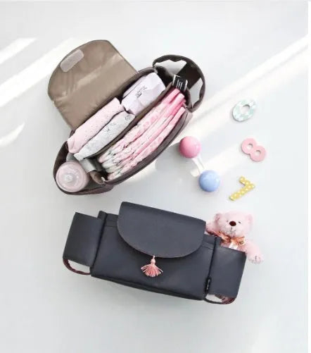 Pink tassel multifunction baby stroller bag organizer attached to stroller handles