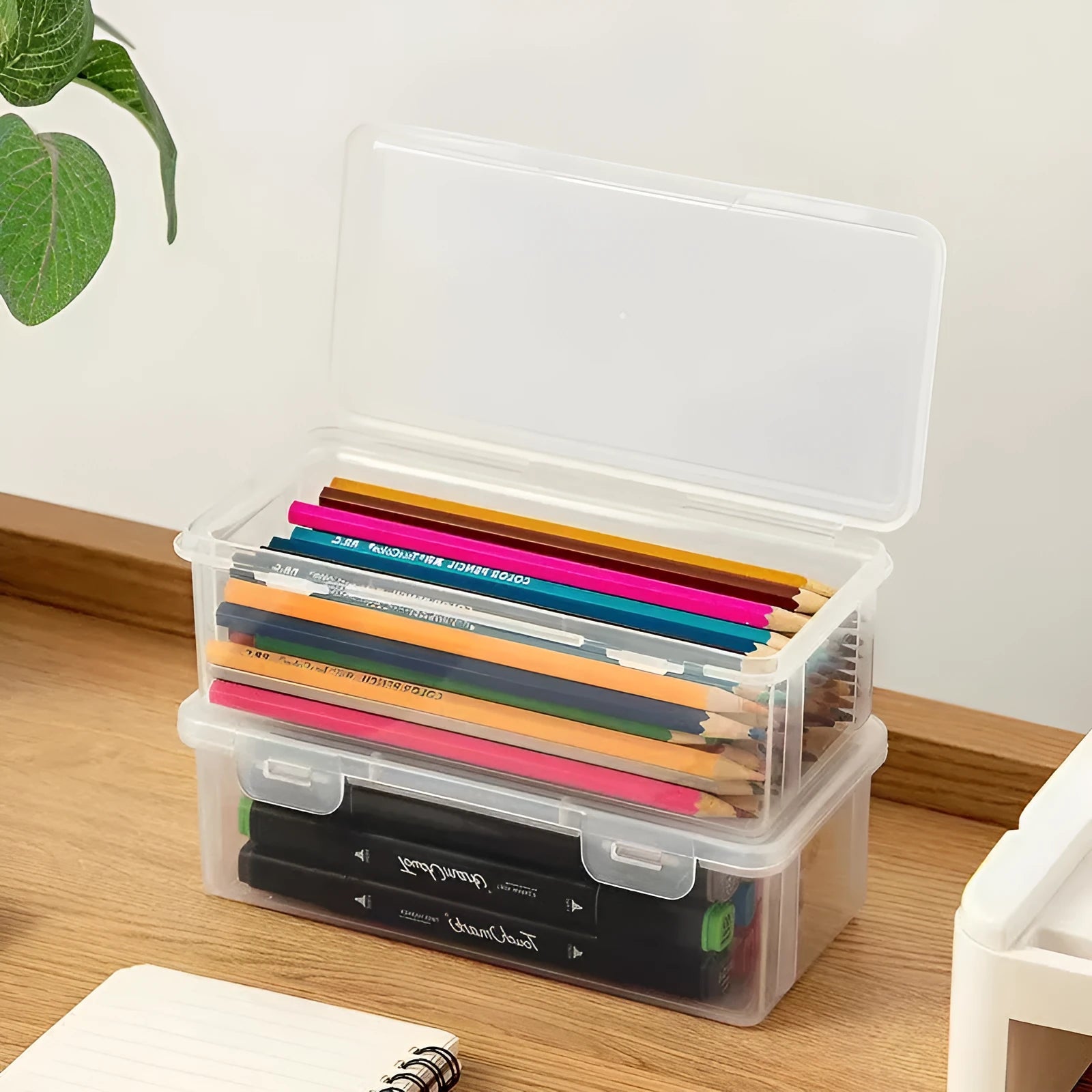 Large transparent plastic stationery storage box holding coloured pencils and crayons.