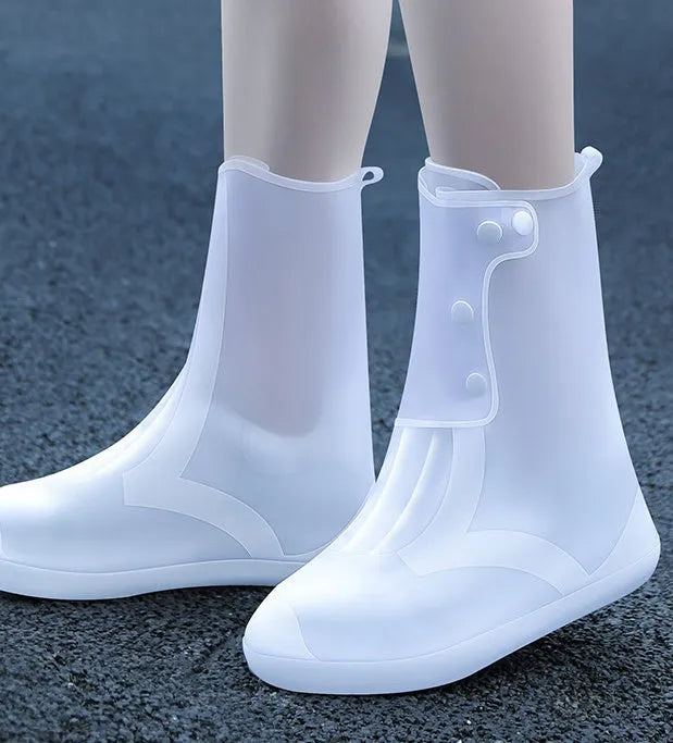 White high-top PVC reusable shoe covers for women on a rainy day background.