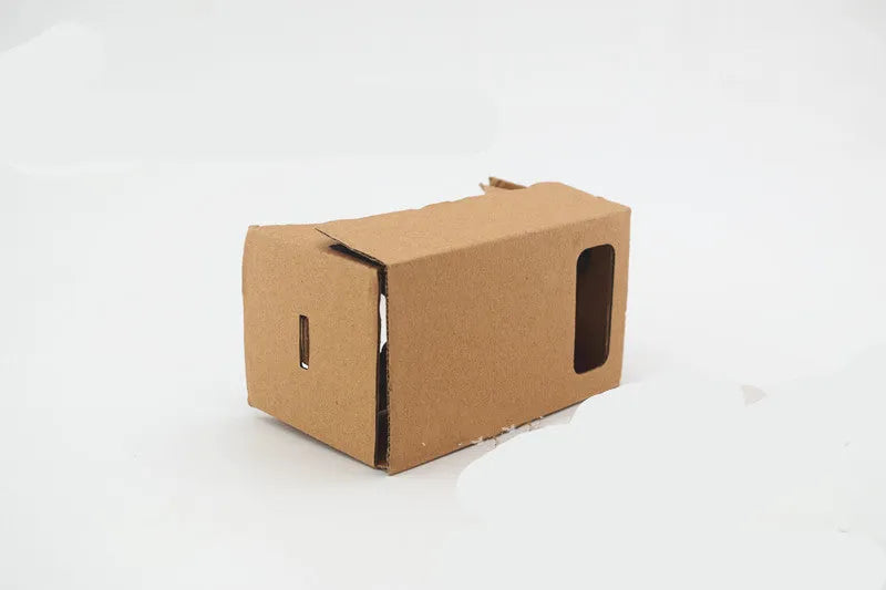 Foldable pink and white VR cardboard glasses headset for smartphones with adjustable strap and 3D lenses.