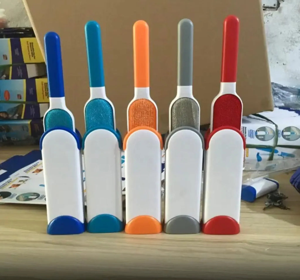 Blue reusable pet hair removal comb with double-sided sticky brush next to its self-cleaning base.