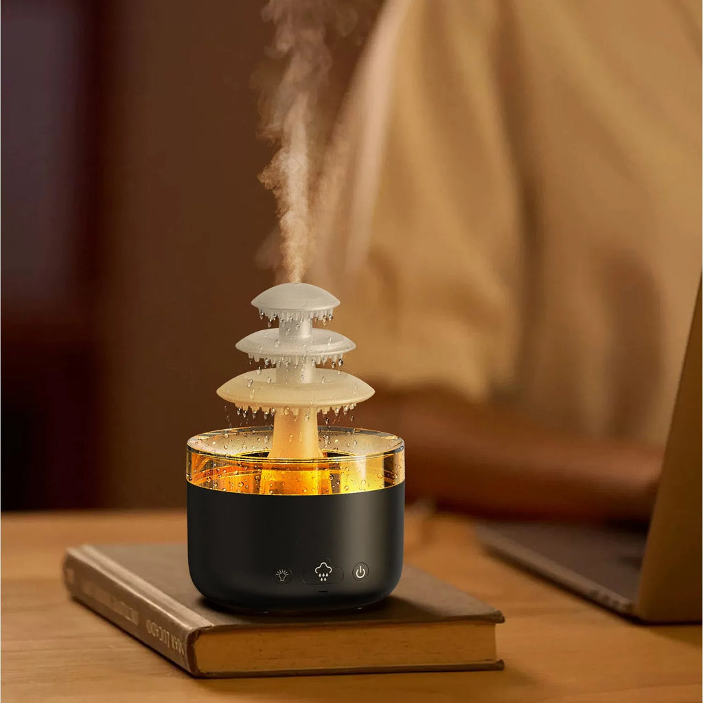 White cloud rain shape ultrasonic humidifier and essential oil diffuser with colourful LED lights on a table.