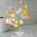 White and red rose flower shaped USB battery LED table lamp with warm white light on a table.