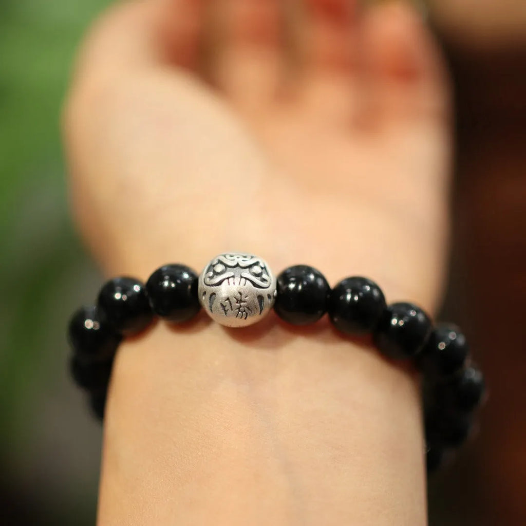 Close-up of a women's black agate bracelet with a sterling silver clasp on an alloy chain.