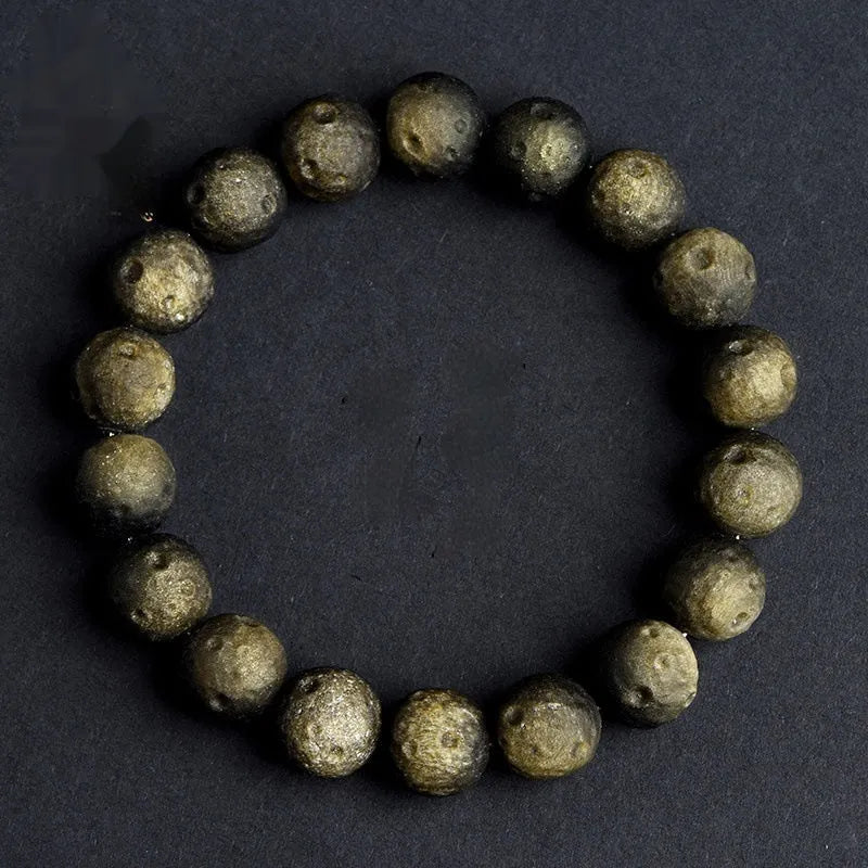 Natural obsidian crater ball bracelet with textured beads in gold or silver stone finish on a wrist.