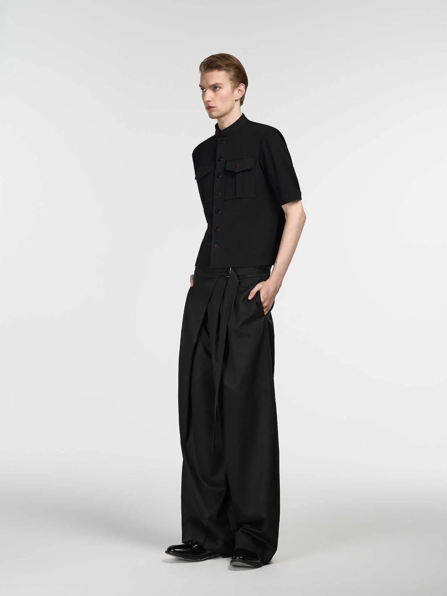 Black straight leg trousers with a single front pleat and an adjustable waistband on a hanger.