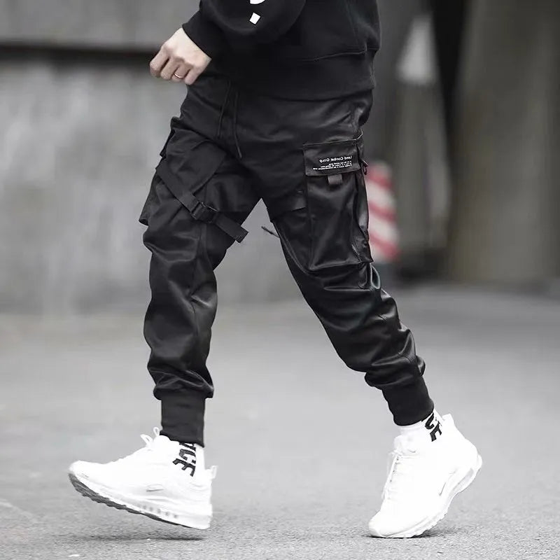 Men's black cotton cargo joggers with drawstring waist and side velcro pockets, loose harem fit