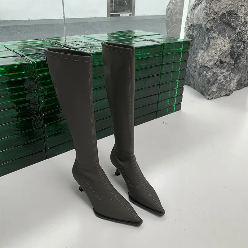 Women's black pointed toe below knee stiletto heel boots with a back zipper on display.