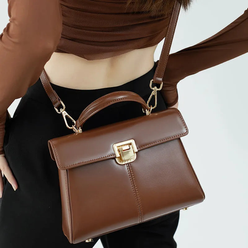 Black genuine leather women's shoulder bag with clasp closure and adjustable strap.