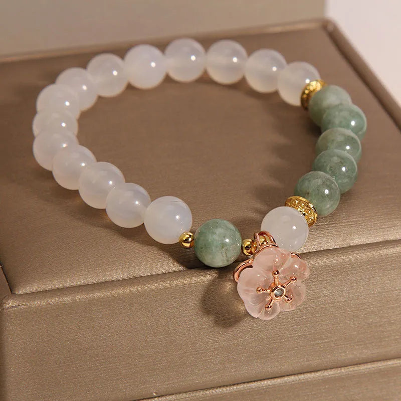 Women's white agate jade flower bracelet on a wrist, showing detailed floral carving.
