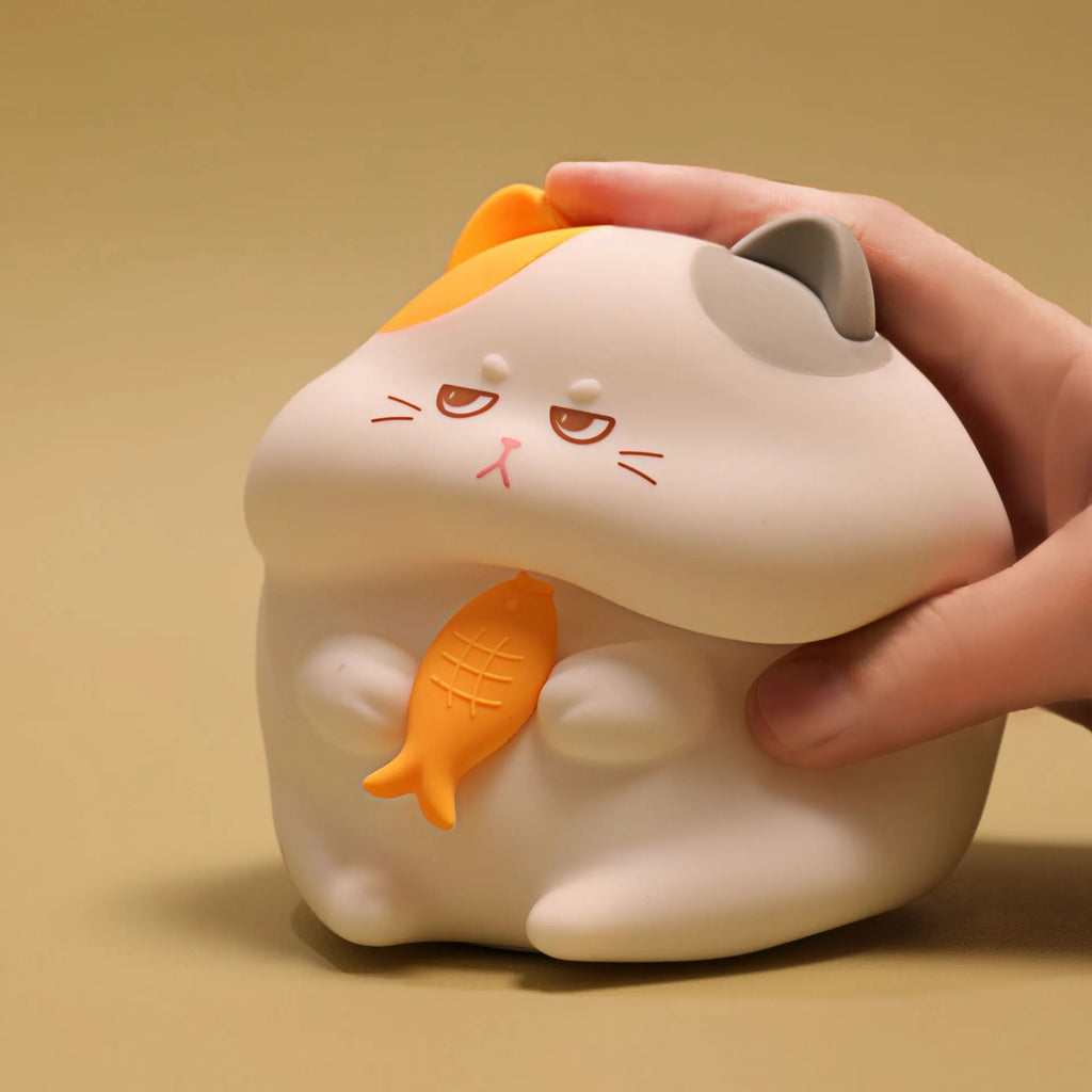 Small greedy cat cartoon desktop night light with yellow fin tuna design on a desk.