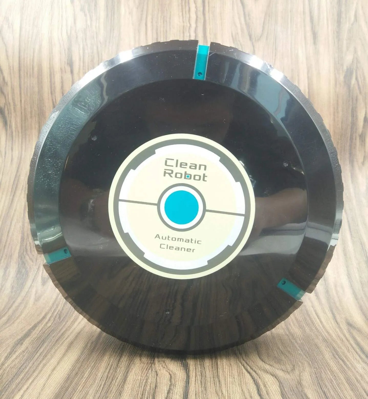 Black automatic robot vacuum cleaner on a wooden floor