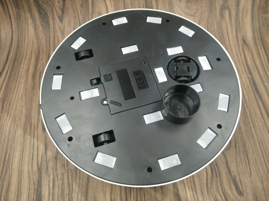 Black automatic robot vacuum cleaner on a wooden floor