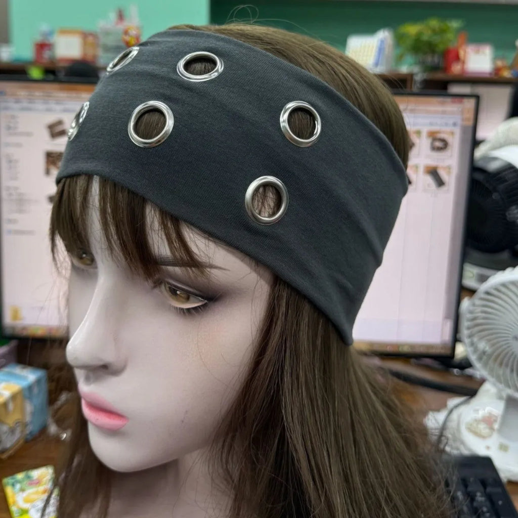 Close-up of a black exercise hair band with a silver hollow metal circle on a person's forehead.