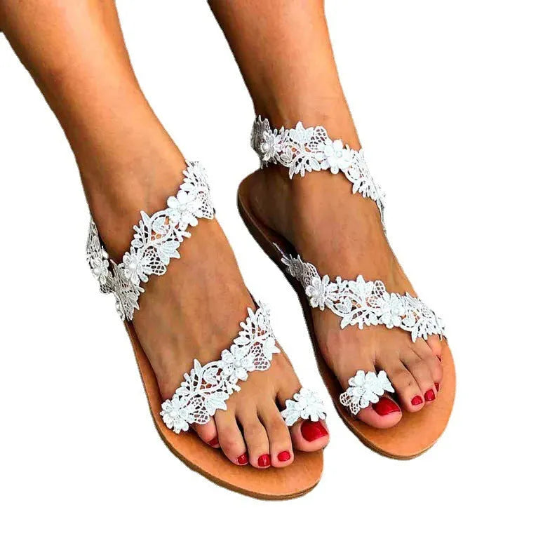 White women's sandals with rhinestone floral decoration on PU upper, slip-on flat design.