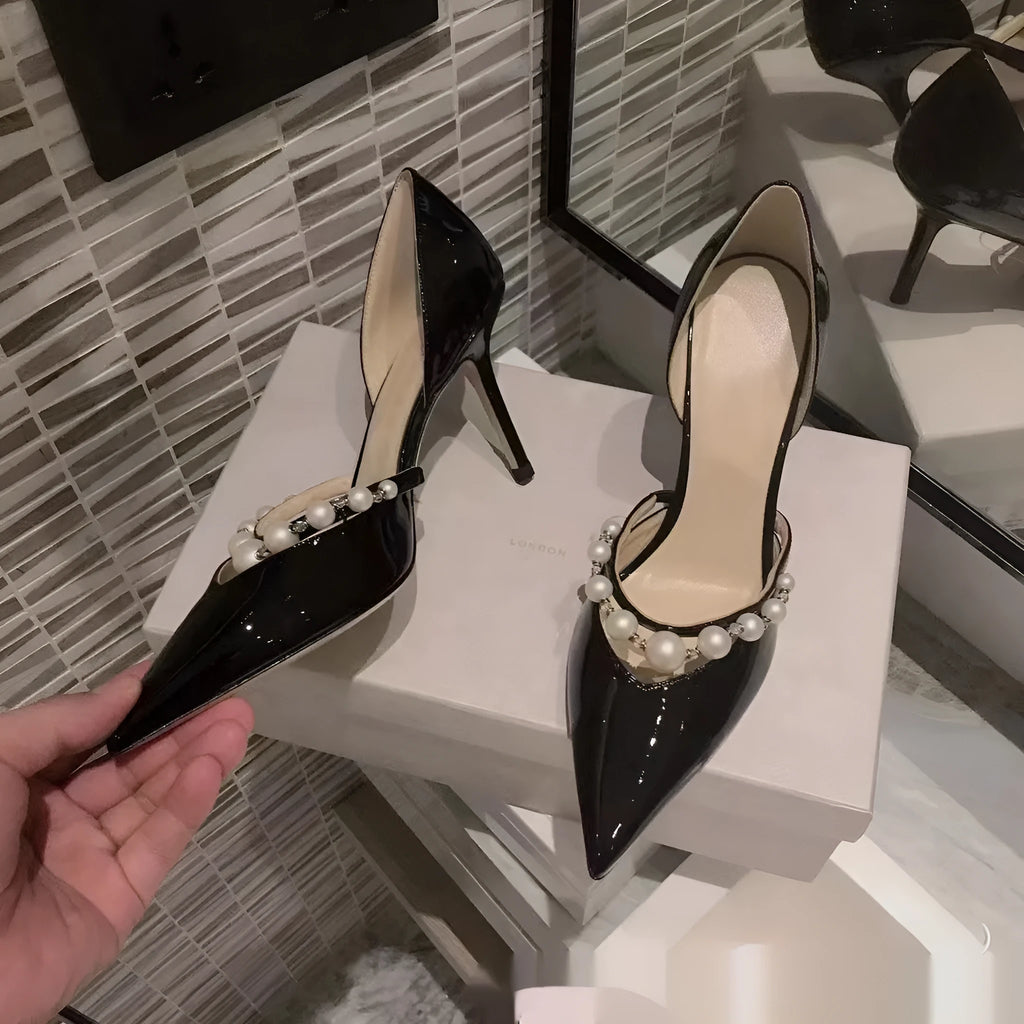 Women's black pointed patent leather stiletto high heel shoes with a glossy finish.