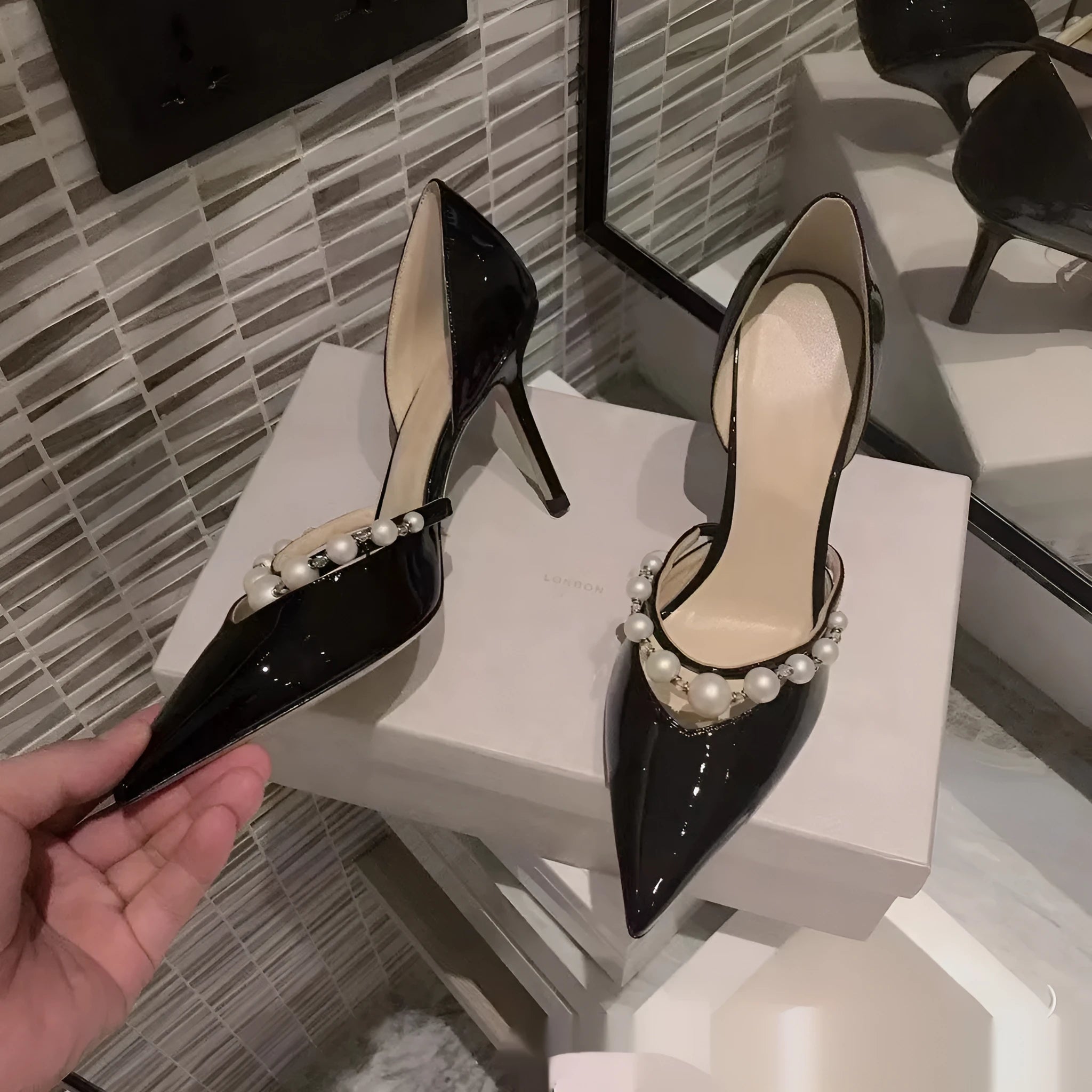 Women's black pointed patent leather stiletto high heel shoes with a glossy finish.