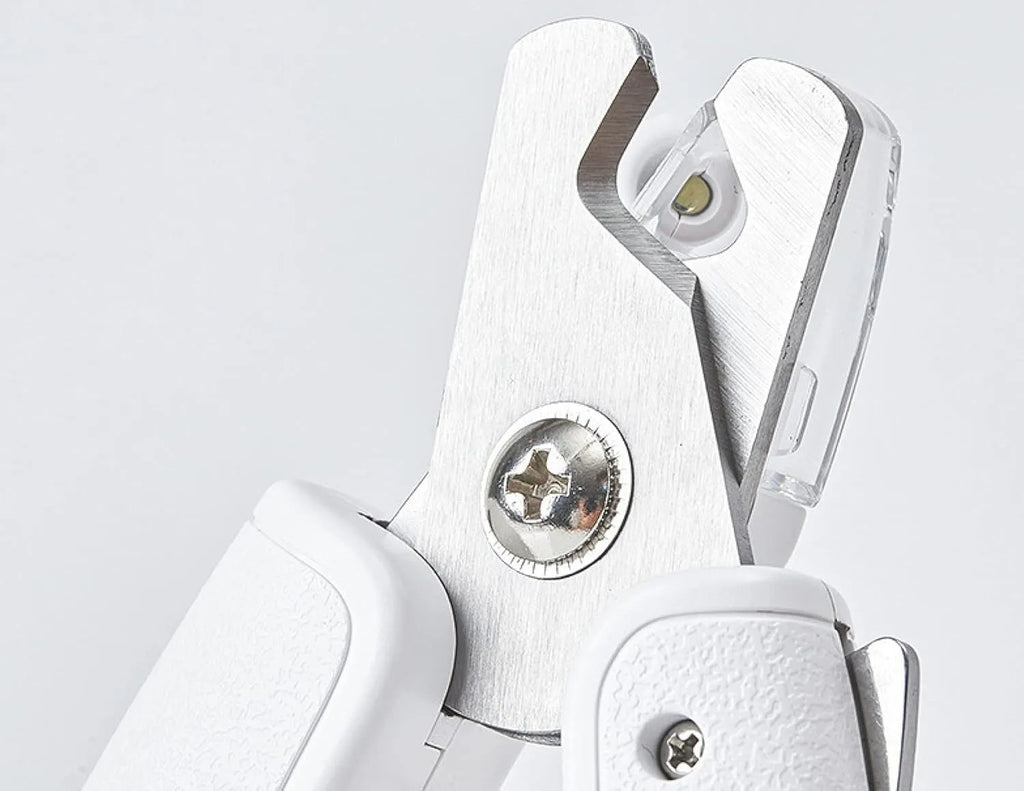 White pet nail clipper with LED light and transparent anti-splash guard on a blue background.