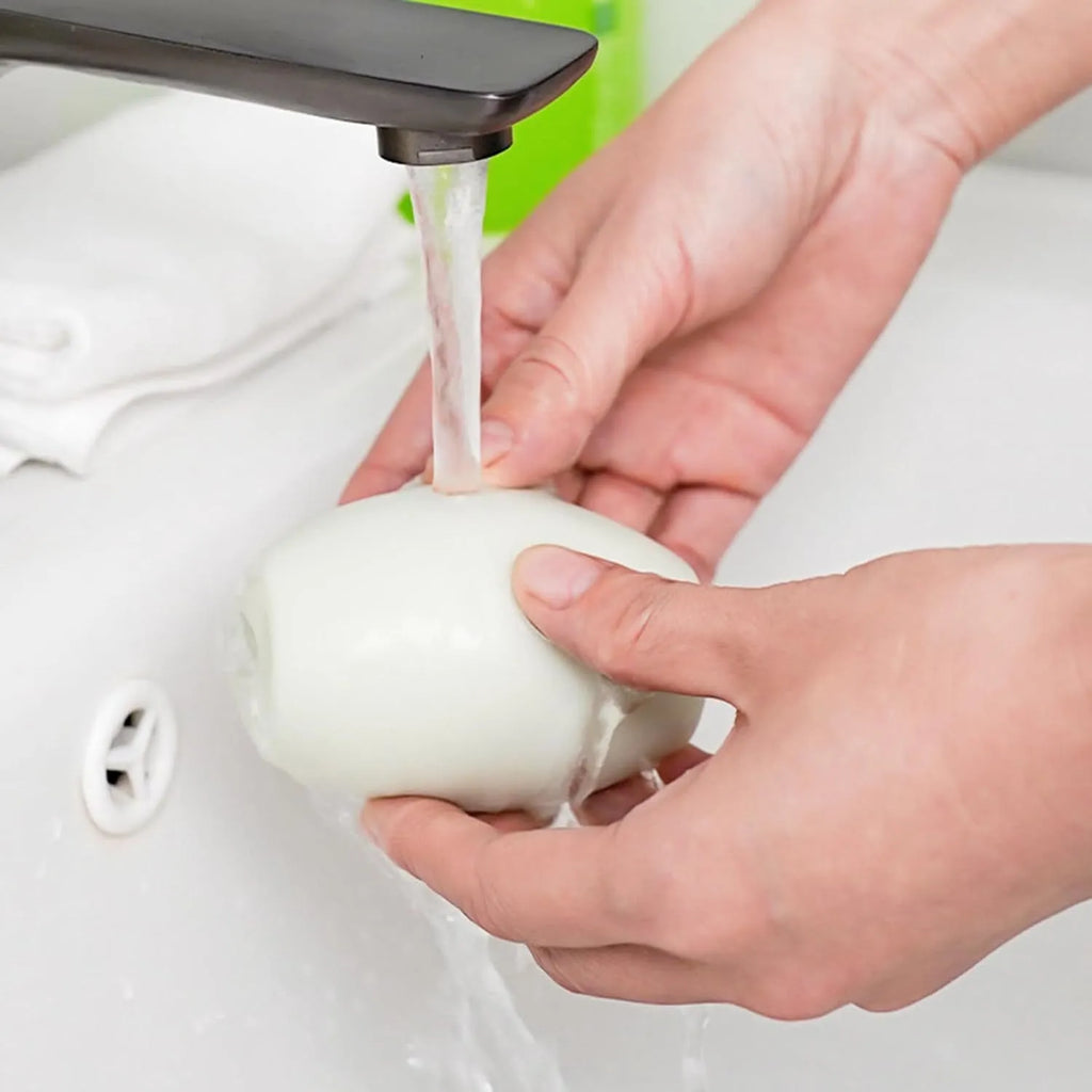 Green or white reusable gel lint roller ball for pet hair removal on fabric.