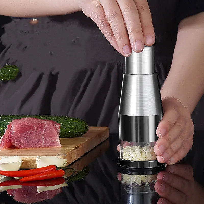 Manual garlic press and onion chopper with stainless steel blades on a kitchen counter.