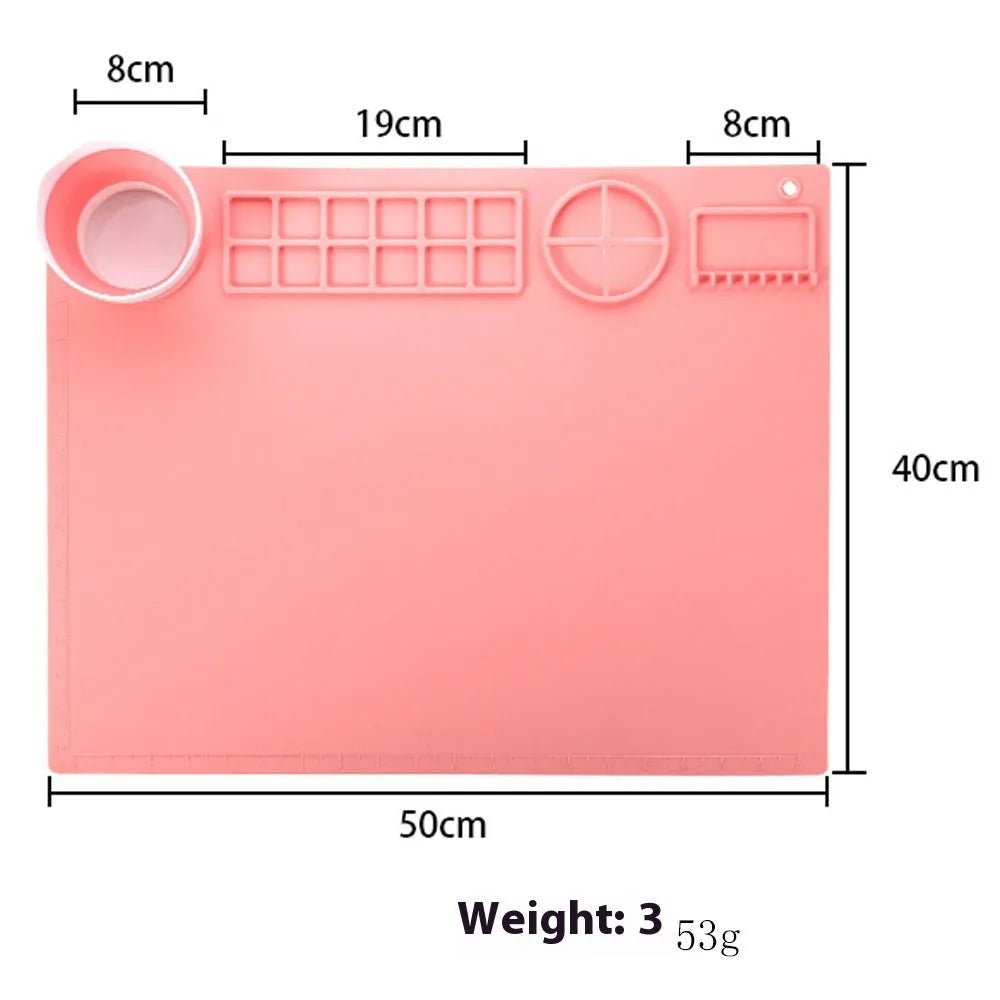 Light blue silicone painting mat measuring 50 by 40 centimetres on a wooden table.