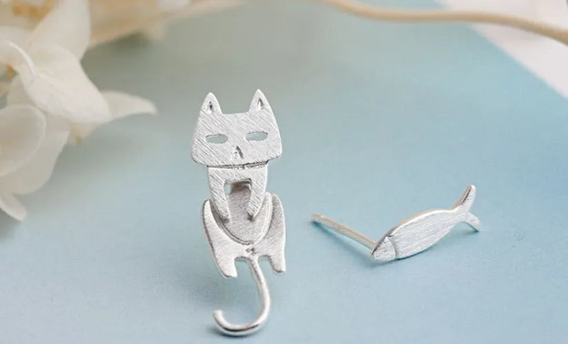 S925 sterling silver stud earrings with asymmetrical cat and fish design on white background