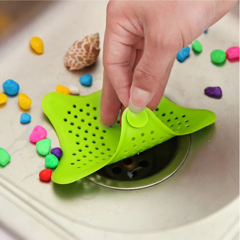 Three silicone starfish-shaped sink drain filters in white blue and green with suction cups