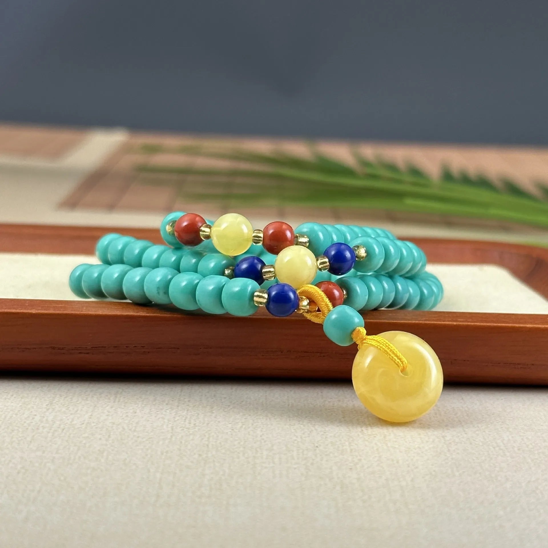 Close-up of a hand-woven turquoise mesh flower pendant on a ball bead necklace, adjustable from 71cm to 80cm.