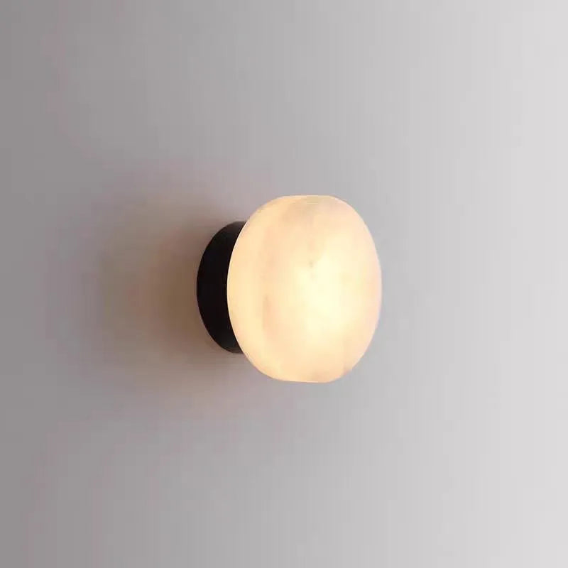 Spanish natural marble round wall lamp with warm light, 130mm diameter, black finish on a bedroom wall