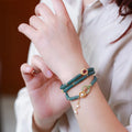 Close-up of a women's blue water jade abacus bead bracelet with three rings, tourmaline, and pearl accents.